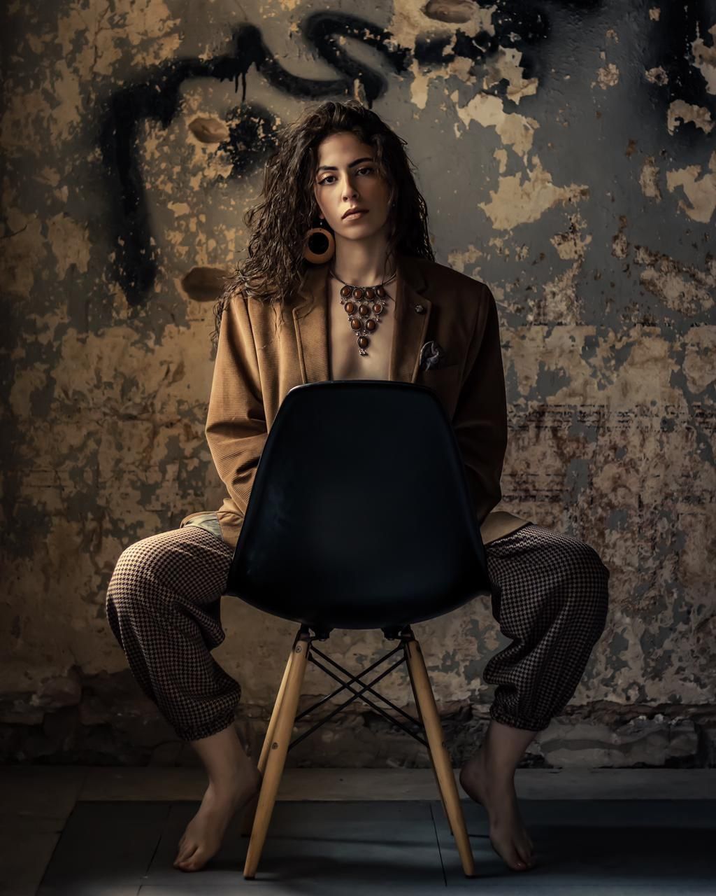 Model seated against a weathered wall