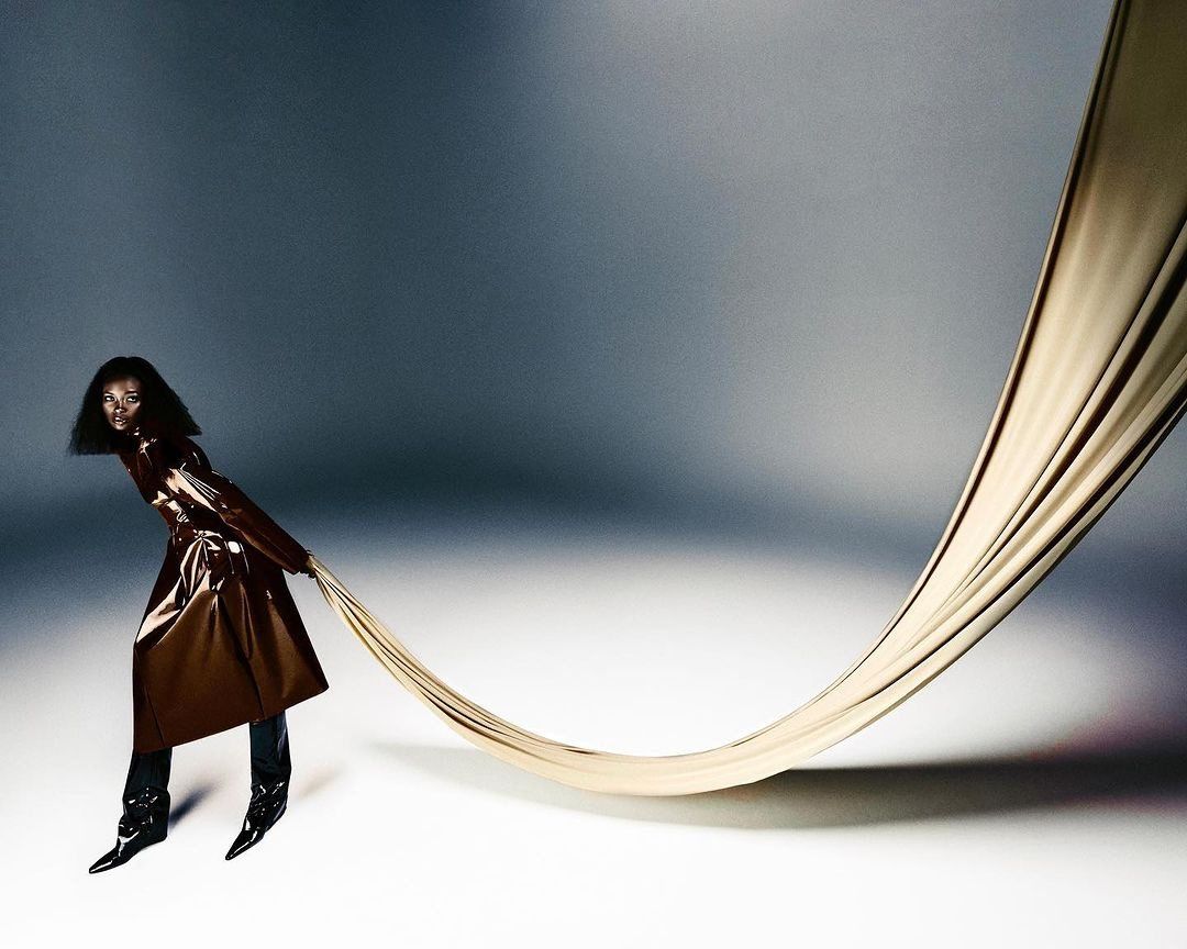 Model pulling a long draped fabric